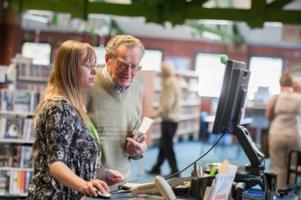 Library staff helping a visitor in Broadstone library, Poole.