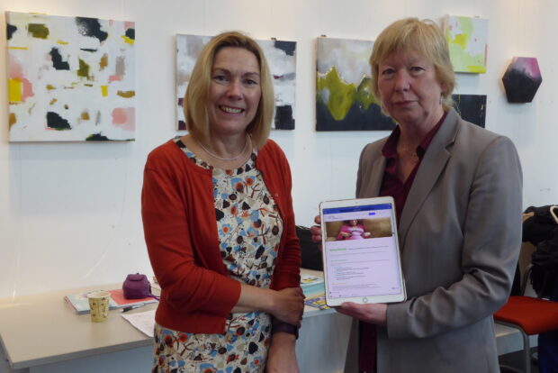 Photo of 2 women showing a tablet with a toolkit on it