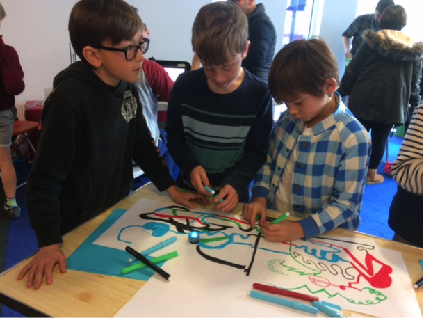 Photo of 3 boys playing using an Ozobot.