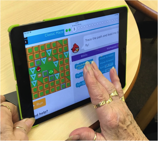 Photo of an older woman using a tablet to code