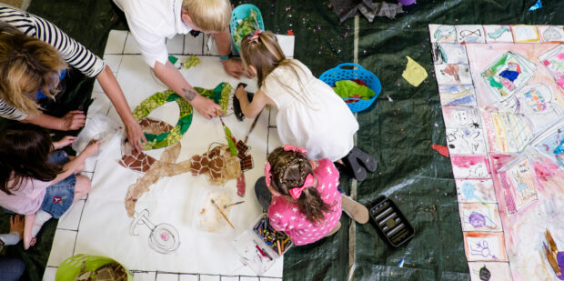 Photo of some children painting on large pieces of paper on the floor