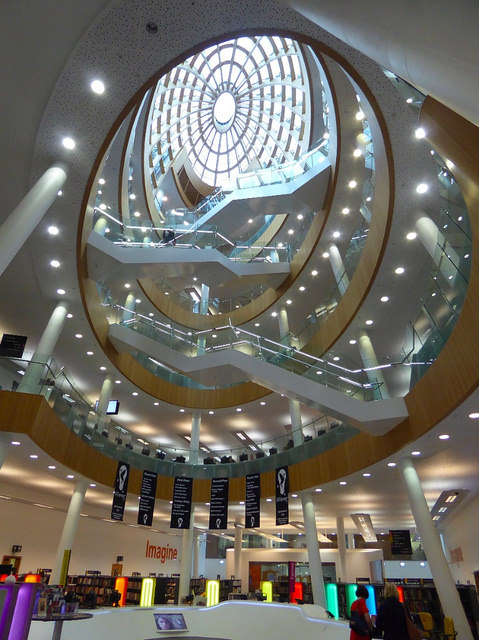 Photo of the inside of a library looking up from the ground floor to the glass dome a few floors above.