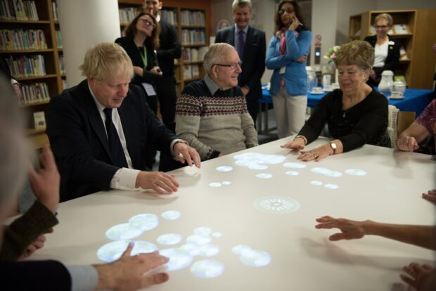 Photo of people around a table with images being projected onto it.