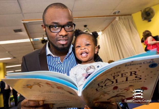 Photo of a young girl reading with her father.