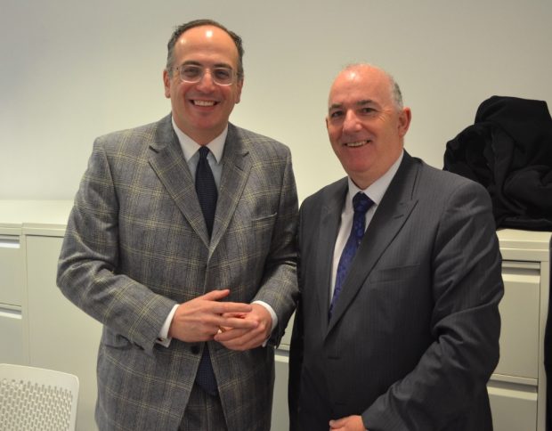 Photo of 2 men standing in a meeting room.