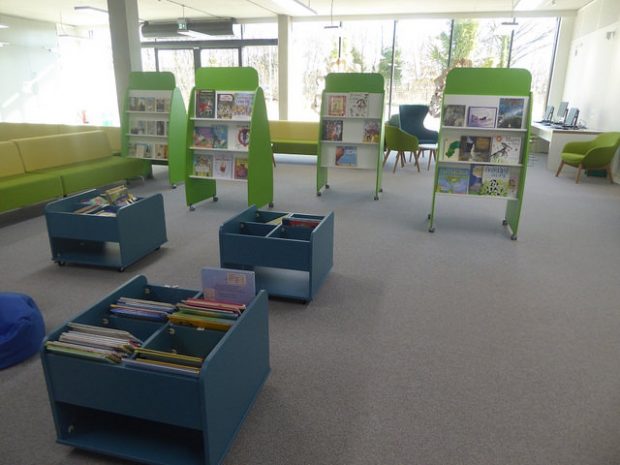 Photo of the inside of a library which is very light with bright green and blue furniture.