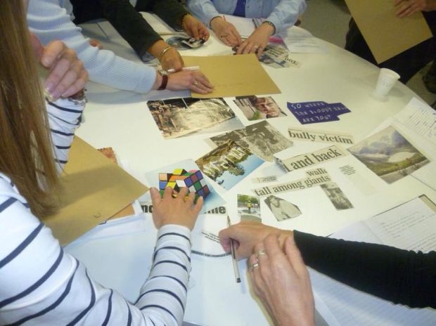 Photo of people moving around photos and newspaper headlines on a table in the library.