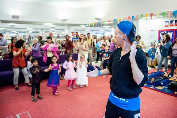 A group of adults and children dancing in the library.