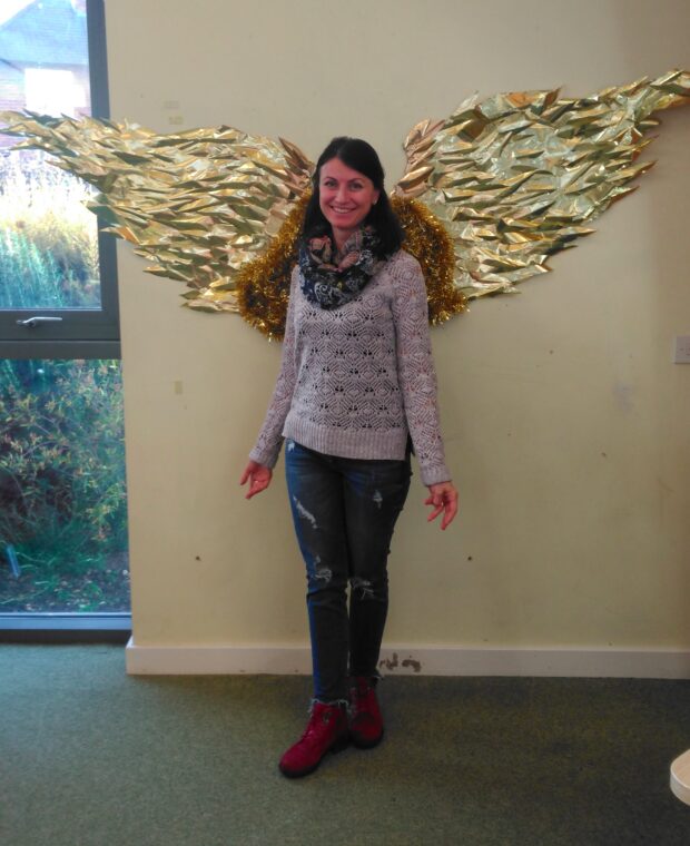 Photo of a woman standing in front of gold angel wings