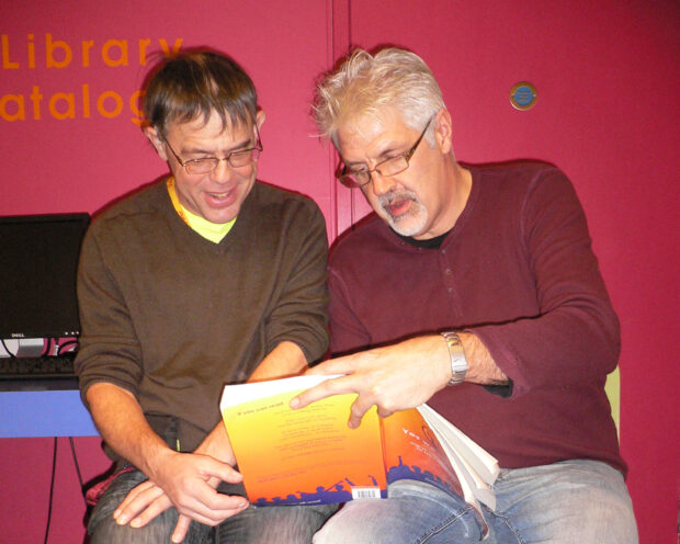 Photo of 2 men reading a Norfolk Reading Pathway book