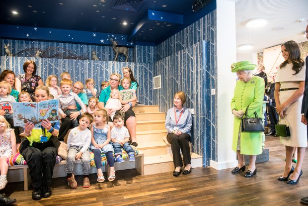 Photo of the Queen and Duchess of Sussex watching storytime in the reading den