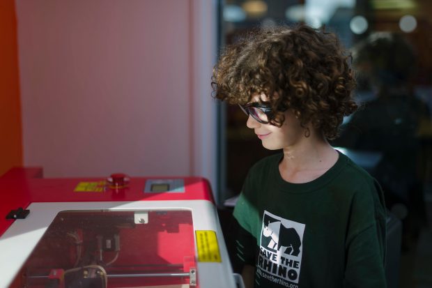 Photo of a boy looking at a piece of equipment in the Fablab