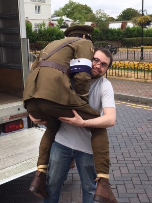 Photo of a man holding a dummy of a man dressed in a soldiers uniform from World War One.