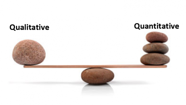 A photo of a see saw with pebbles on each end, illustrating the balance needed between quantitative and qualitative date