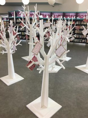 Photo of Redbridge Unsaid exhibition, consisting of a group of large model white trees with coloured labels tied on to them in place of leaves