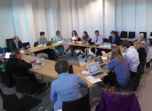 Photo of the Taskforce meeting - people sitting around tables in a square shape.