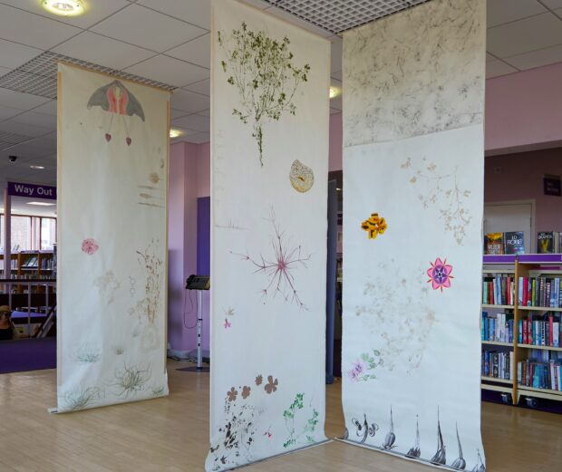 Photo of banners hanging from the library ceiling, showing plant and flower artwork