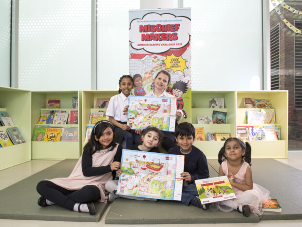 Photo of a group of children holding posters promoting the Summer Reading Challenge