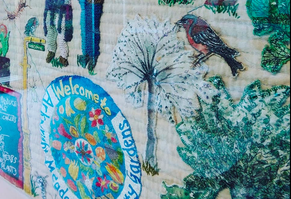 Photo of the detail of an embroidered wall hanging, showing a bird and a tree