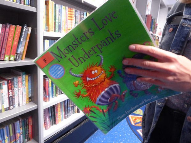 Photo of a closeup of someone reading the child's picture book Monsters love underpants, in a library