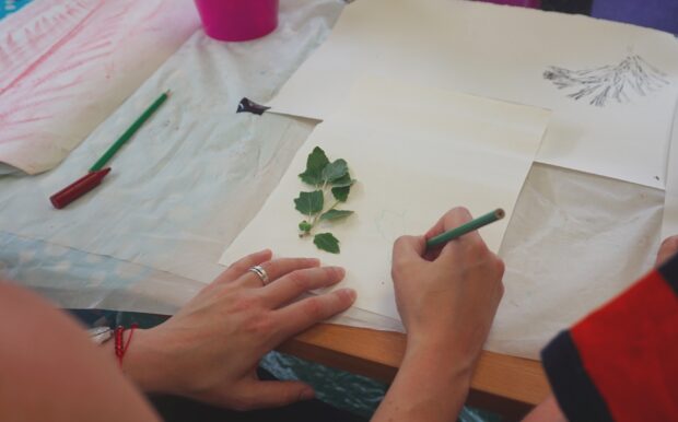 Photo of a close up of a hand drawing a sprig of leaves