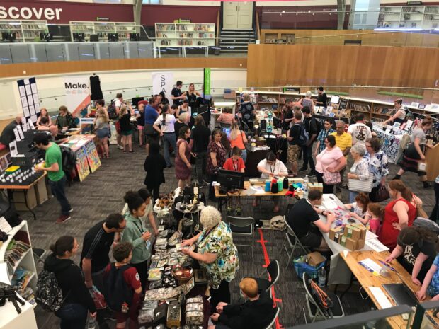 A photo of a space in the library full of people going around different stalls