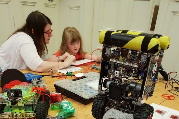 A photo of a woman and girl who are creating a circuit for a robot