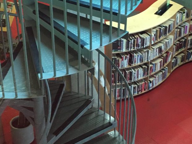 Photo of the inside of a library with a spiral staircase