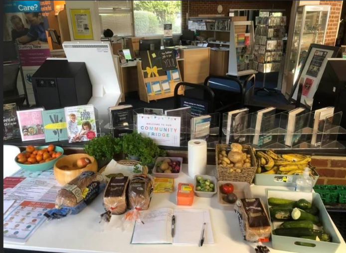 Table with various food items and 'Community Fridge' sign