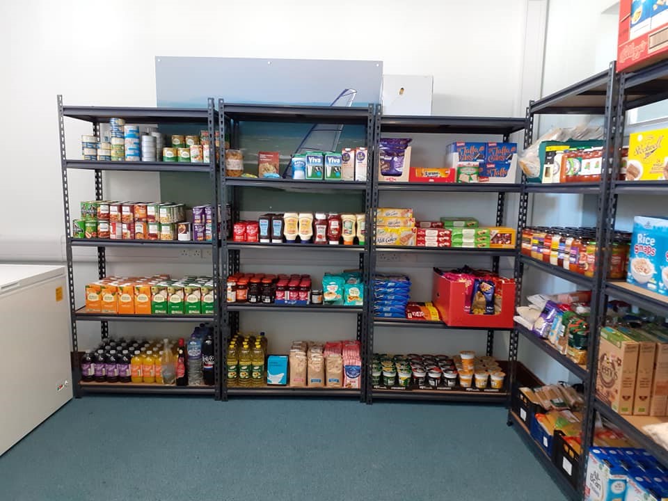 Metal shelving units with tins and packets of food stacked on them